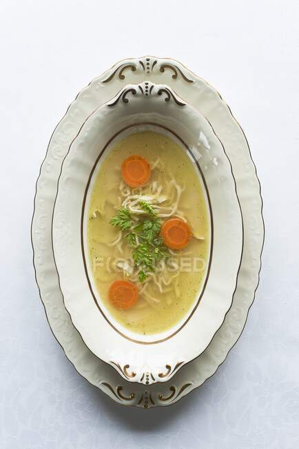 Caldo de pollo transparente con fideos y zanahorias - foto de stock