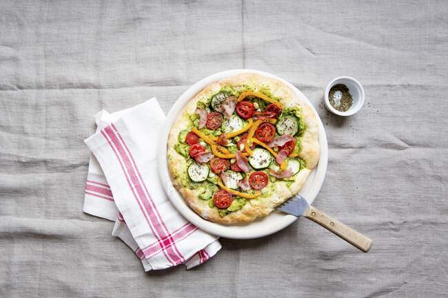 Pizza con aguacate, calabacín, tomates, pimientos y jamón - foto de stock
