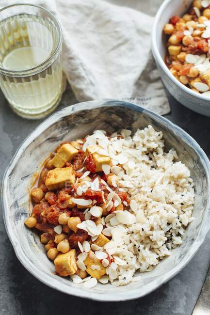 Veganes Curry mit Kichererbsen und Tofu, serviert mit braunem Reis und Mandelflocken — Stockfoto