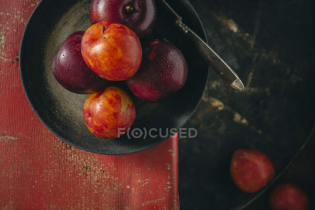 Fresh plums in black pan with knife — Stock Photo