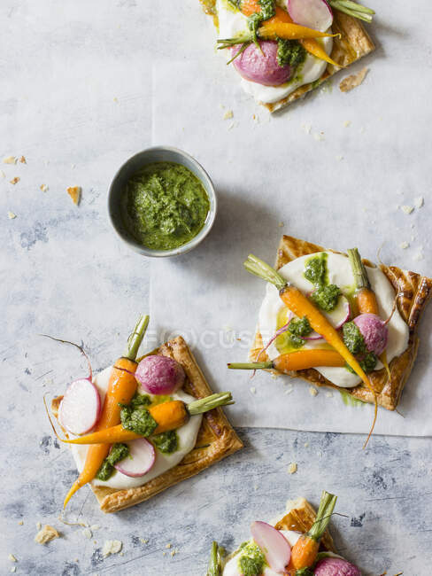Puff pastry tart with lemon feta and cream cheese spread, roasted baby carrots, radishes and carrots - foto de stock