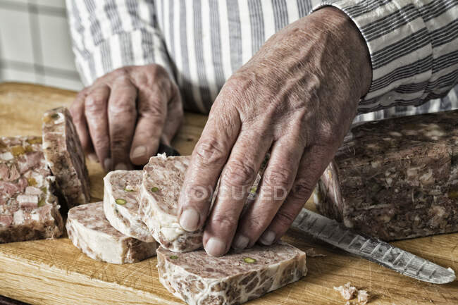Un hombre cortando paté en rodajas gruesas - foto de stock