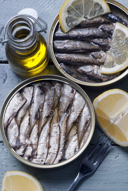 Spats in oil with lemon, and a bottle of olive oil on a wooden table — Stock Photo