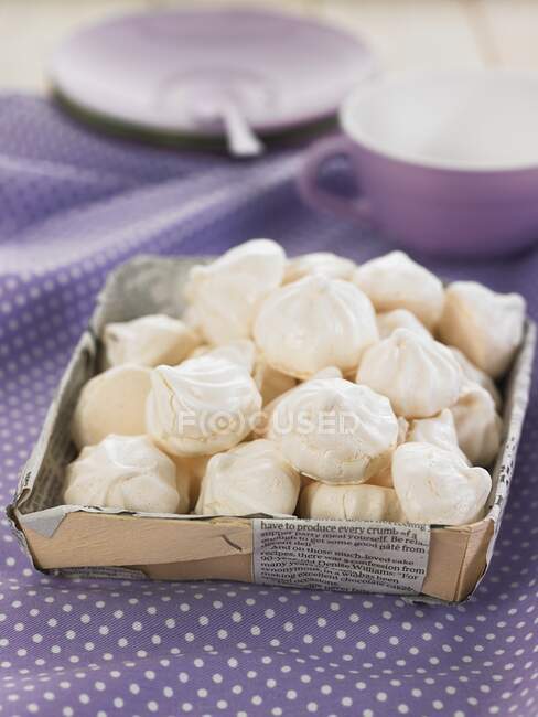 Pile of meringues in box on purple tablecloth — Stock Photo