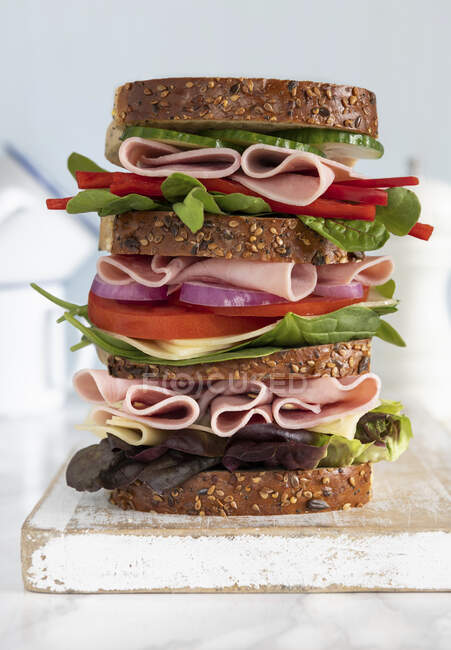 Triple-decker sandwich on wooden board — Stock Photo
