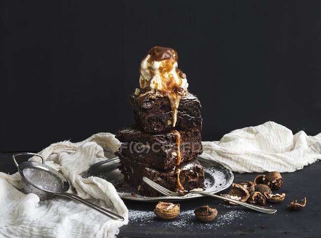 Fudgy Brownies torre con caramelo salado, nueces y helado - foto de stock