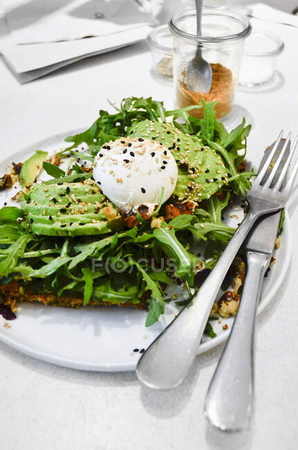 Avacado and poached eggs on rocket and toast with sprikled sesame seeds — Stock Photo