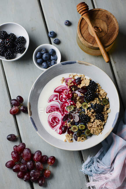 Миска з йогуртом з цільнозерновим вівсяним м'ясом, ягодами та нарізаним виноградом — стокове фото