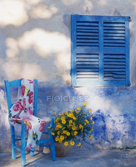 Silla de jardín con tela y flores por pared de la casa - foto de stock