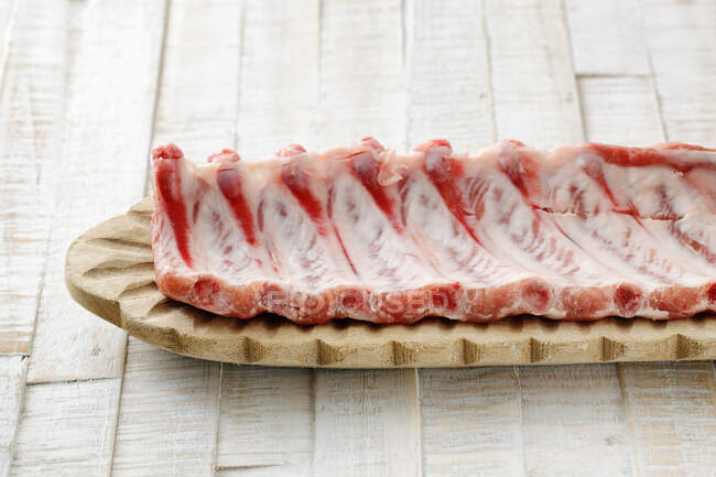 Côtes de porc crues sur planche de bois — Photo de stock