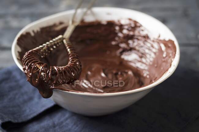 Chocolate fondue with cream and nuts on a wooden table — Stock Photo