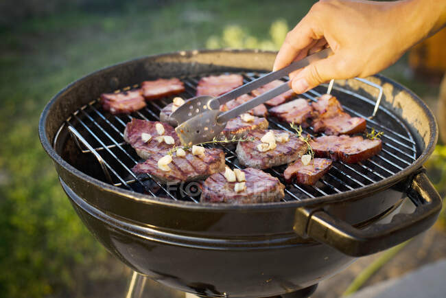 Beef steaks and bacon on a grill — Stock Photo