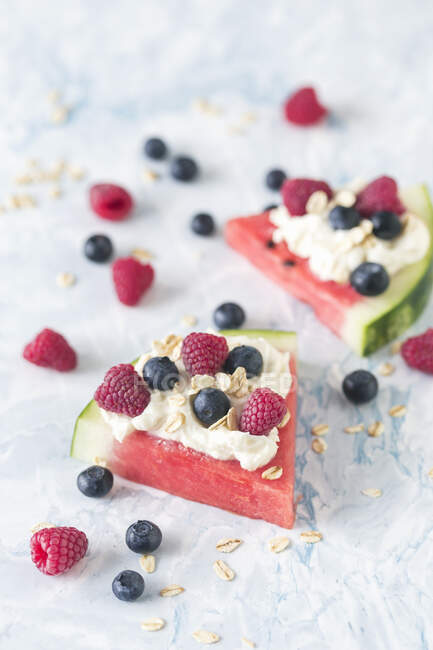 Watermelon slices with whipped cream and fresh berries on marble surface — Stock Photo