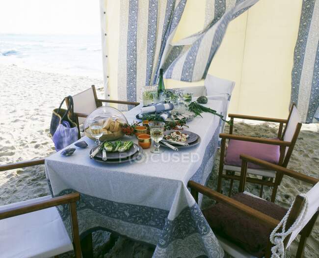 Накрытый стол в пляжной палатке на пляже — стоковое фото