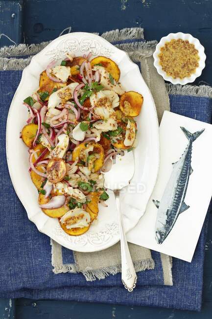 Baked potato slices, onion and smoked cod salad with mustard dressing — Stock Photo