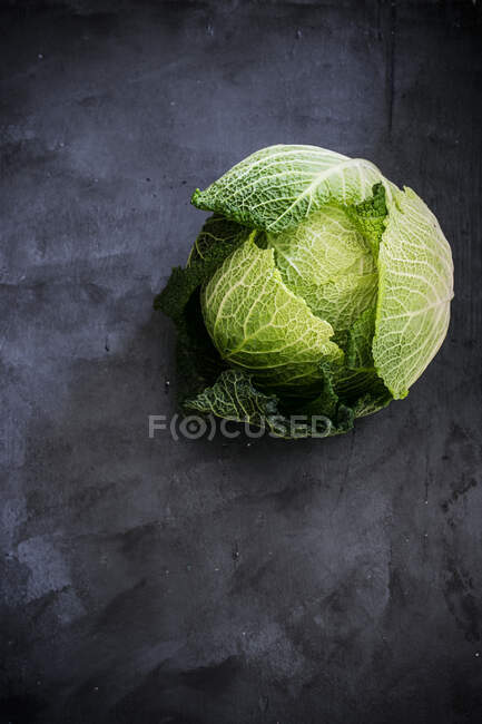 Whole savoy cabbage on a dark surface — Stock Photo