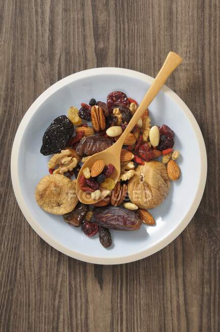Dried fruit and nuts in a bowl with a wooden spoon — Stock Photo