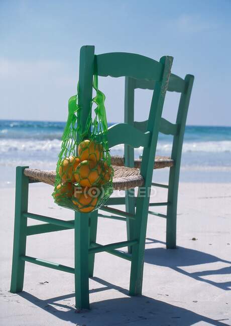 Deux chaises longues, une avec des oranges, sur la plage — Photo de stock