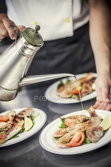 Hand finished grilled fish and shrimp on a plate with olive oil — Stock Photo