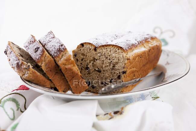 Пасхальный хлеб с смородиной и орехами, нарезанный на тарелке — стоковое фото