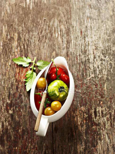 Various tomatoes in a saucer on a wooden background — Stock Photo