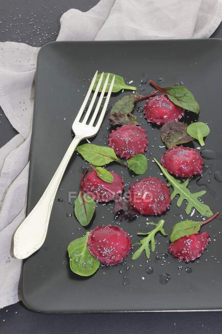Plan rapproché de délicieux raviolis à la betterave aux feuilles de salade mélangées — Photo de stock