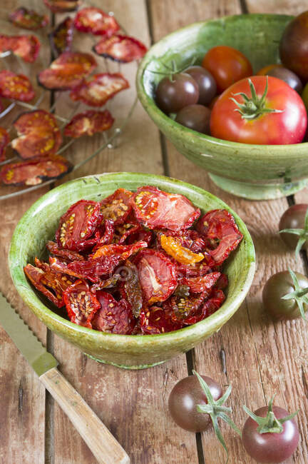 Tomates secos en un estante de alambre y en un tazón de cerámica - foto de stock