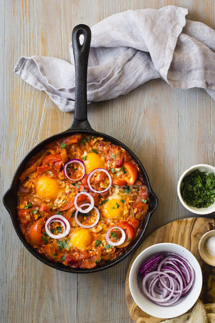 Shakshuka com pimentas e tomates, salada picada, anéis de cebola vermelha e sal — Fotografia de Stock