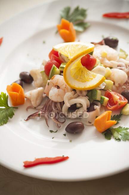 Fischsalat mit Tintenfisch, Garnelen, Zucchini, Oliven und Kirschtomaten — Stockfoto