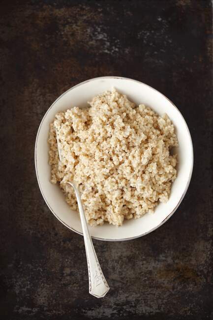 Bowl of rice with spoon on a black background — Stock Photo