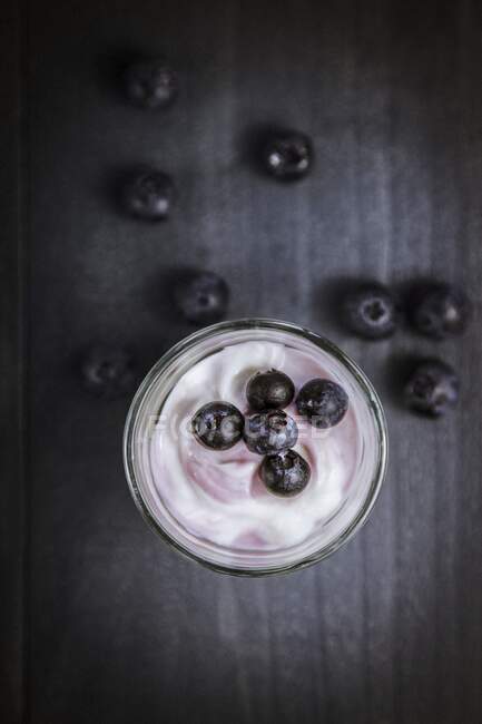Yogurt with blueberries in jar and berries on table — Stock Photo