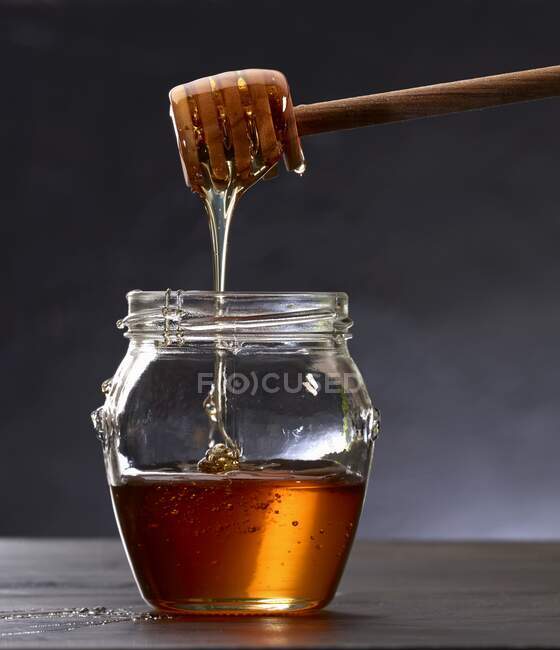 Honey dripping from a honey dipper — Stock Photo