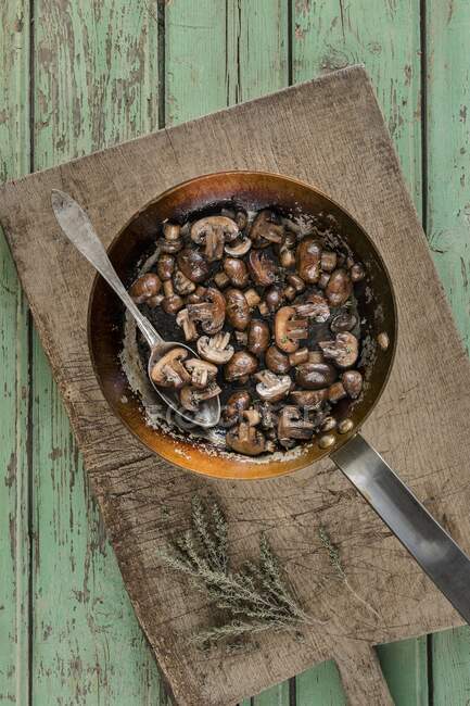 Braune Pilze glasiert in Butter Marsalawein und Thymian in rustikaler Pfanne mit Löffel auf hölzernem Schneidebrett — Stockfoto
