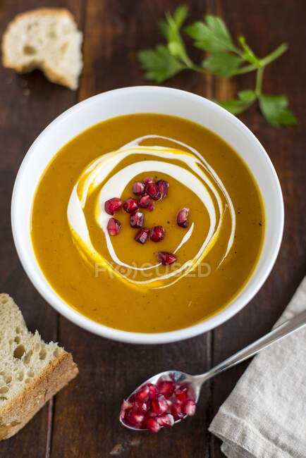 Cream of pumpkin soup with pomegranate seeds in a white bowl — Stock Photo
