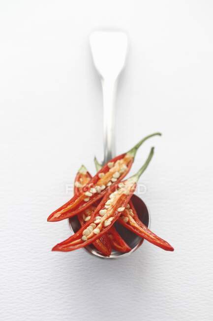 Peperoncini rossi freschi tagliati a fette su un cucchiaio d'argento con sfondo bianco e spazio per il testo — Foto stock