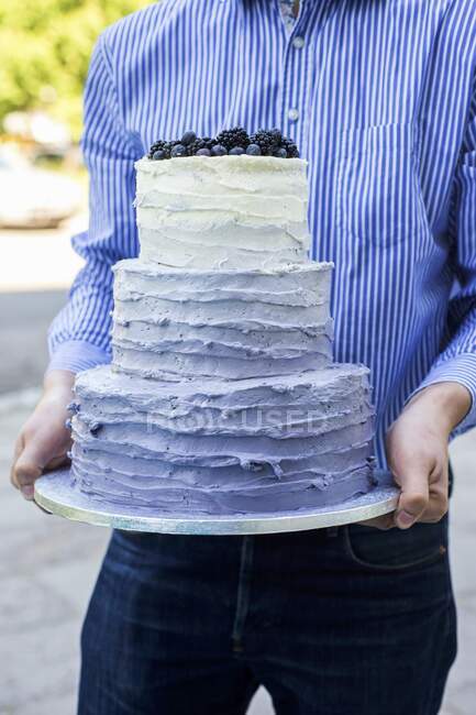 Мужчина, держащий трехъярусный свадебный торт — стоковое фото