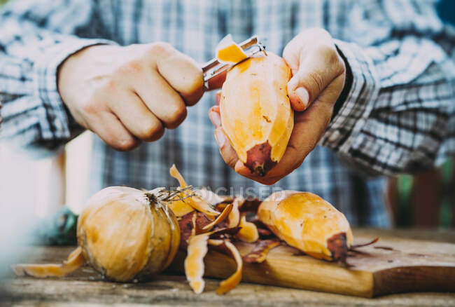 A man peeling fresh sweet potatoes — Stock Photo