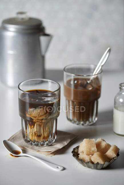 Холодный кофе в стакане со сливками и коричневыми кубиками сахара — стоковое фото