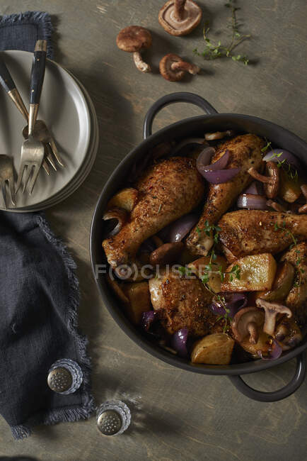 Pollo con patatas, champiñones y cebollas rojas en una lata para asar - foto de stock
