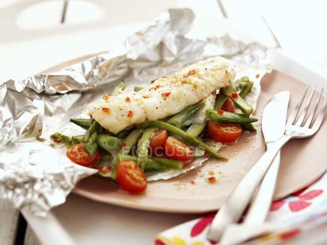 Cod with asparagus and tomatoes in foil — Stock Photo