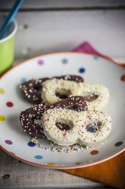 Assiette de biscuits avec glaçures au chocolat et perles de sucre colorées — Photo de stock