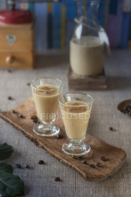 Creamy coffee liqueur in a carafe and served over ice in liqueur glasses — Stock Photo