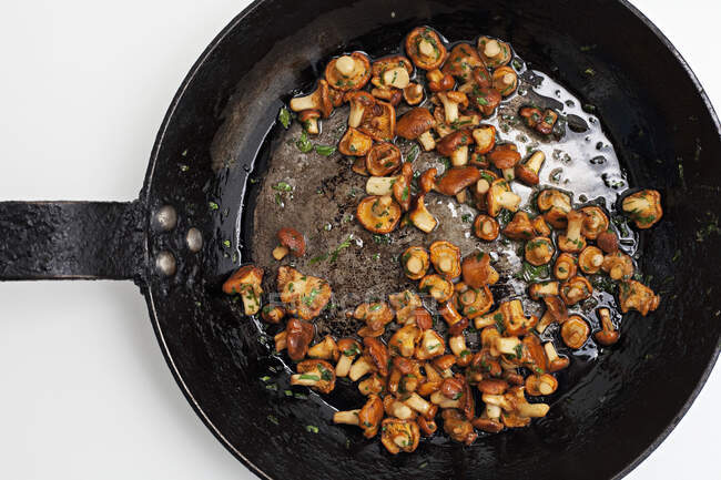 Дикие смешанные грибы, жарящиеся на сковороде с маслом и травами — стоковое фото