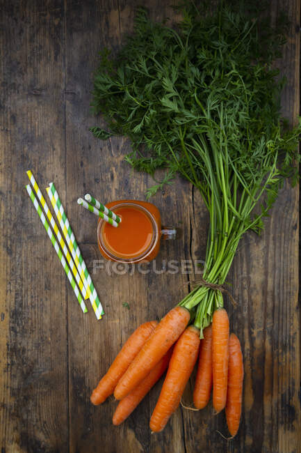 Un batido de zanahoria con pajitas en un tanque (visto desde arriba) - foto de stock
