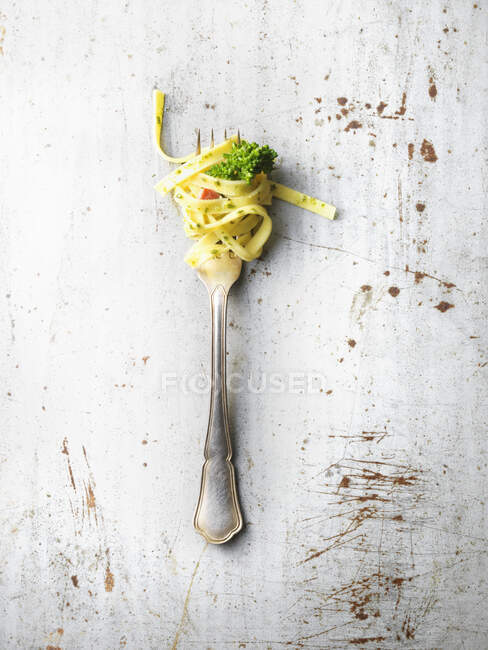 Forkful of Tagliatelle with stem broccoli on rustic surface — Stock Photo