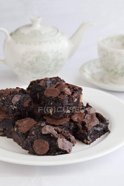 Chocolate brownies with teapot in background — Stock Photo
