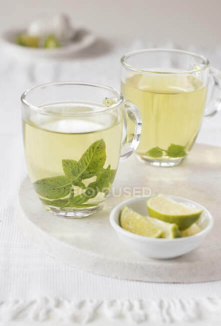 Close-up de delicioso chá de hortelã em duas xícaras claras em branco — Fotografia de Stock