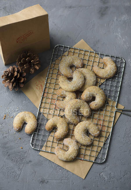 Vanilla crescents on cooling rack with pine cones and small box — Stock Photo