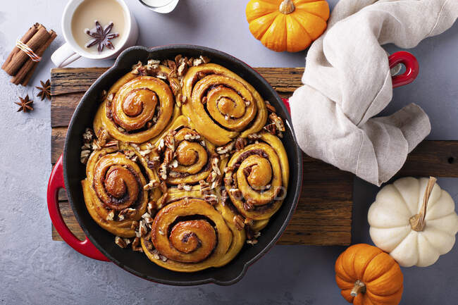Pumpkin cinnamon rolls in a cast iron pan with nuts and sugar glaze — Stock Photo