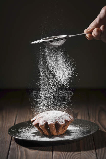 Homem polvilha açúcar de confeiteiro sobre biscoitos — Fotografia de Stock